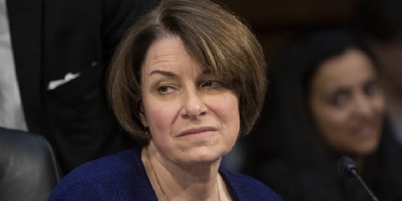 minnesota senator amy klobuchar frowning while sitting at a panel