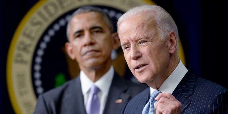 joe biden standing in front of barack obama at podium