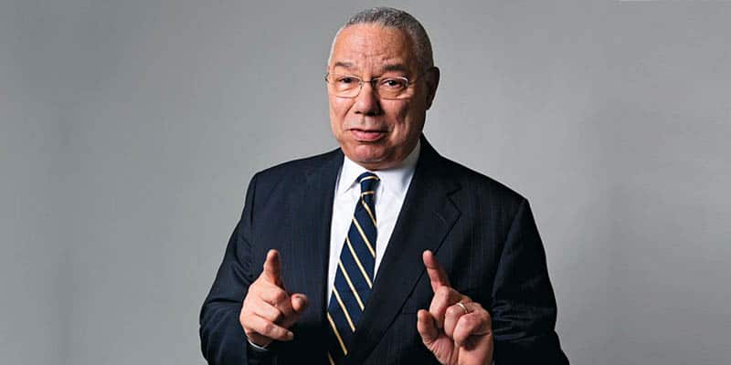 Colin Powell pointing his index fingers upwards