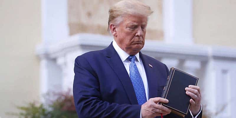 Trump holding and looking at a bible