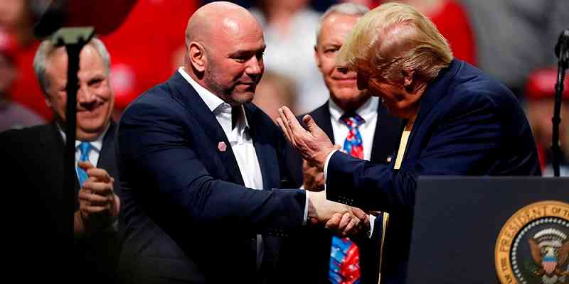 Dana White shaking hands with Donald Trump as he approaches a podium