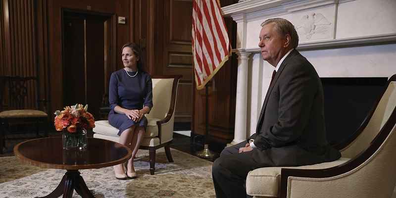 Amy Coney Barrett sitting next to Lindsey Graham