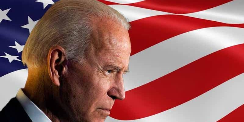 Joe Biden in profile in front of an American flag