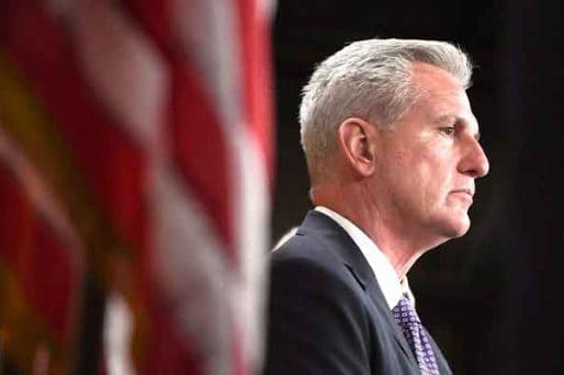 Former US House Speaker Kevin McCarthy next to a US flag