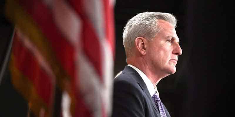 Former US House Speaker Kevin McCarthy next to a US flag